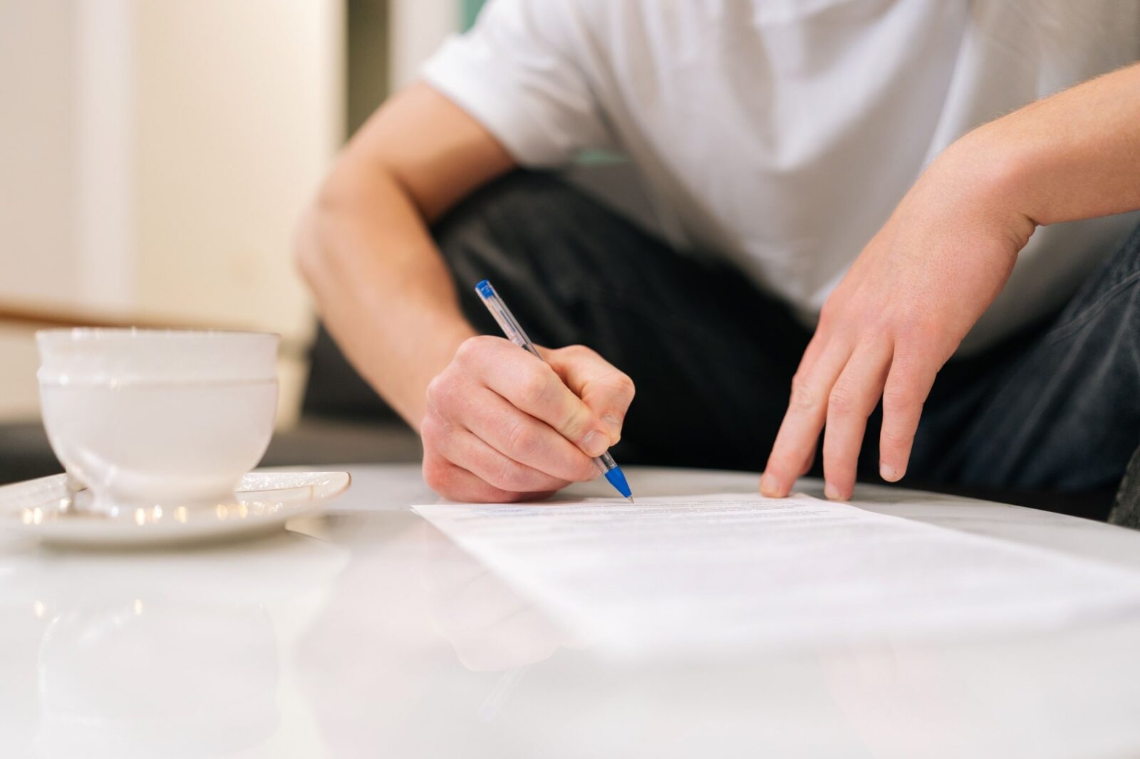 hands of male signing papers sitting at table